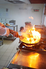 Image showing chef in hotel kitchen prepare food with fire