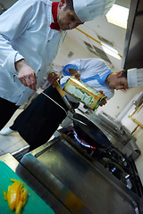 Image showing chef in hotel kitchen prepare food with fire