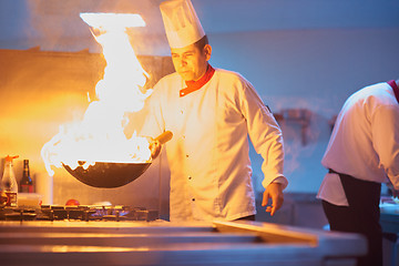 Image showing chef in hotel kitchen prepare food with fire