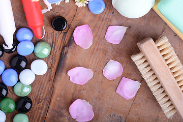 Image showing comb, sea salt, spa stones and flower petals on wooden table, closeup