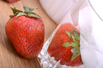 Image showing Strawberry on wooden plate and strawberry frozen with ice in cup