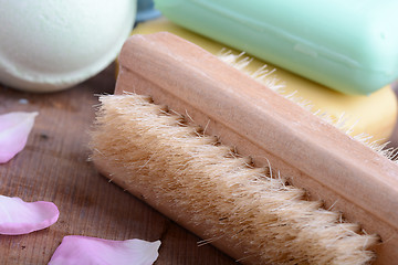 Image showing soap, comb, sea salt, spa stones and flower petals on wooden table, close up