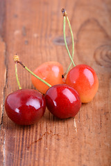 Image showing wooden plate with dark red juicy cherries close up