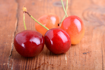 Image showing wooden plate with dark red juicy cherries close up