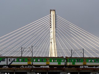 Image showing Train passing in front of a suspension bridge