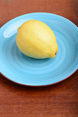 Image showing Whole lemon on a blue plate on wooden background