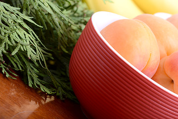 Image showing bananas and apricots on red plate, close up