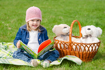 Image showing Happy little girl with a book on a picnic