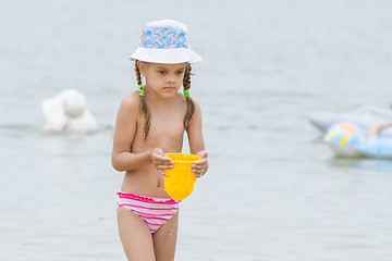 Image showing Five-year girl on the beach carrying water in a bucket