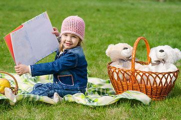 Image showing Happy girl showing the book on picnic
