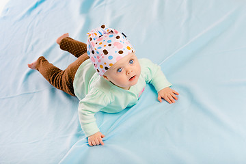 Image showing blue-eyed baby in hat crawling