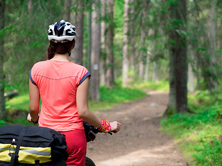 Image showing Woman riding a bike on the forest trail in sunny day