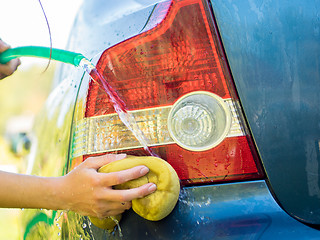 Image showing Hand washing rear lights of blue car by sponge