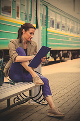 Image showing beautiful woman traveler taking notes in a notebook