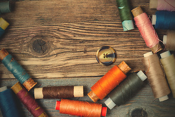 Image showing one vintage button and coils of colored threads