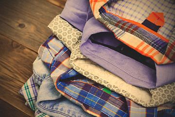 Image showing stack of colored cotton shirts on a wooden shelf