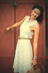 Image showing Smiling pretty middle-aged woman in a white dress with a bag