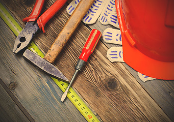 Image showing Vintage hammer, pliers, screwdriver, tape measure, a bright helm