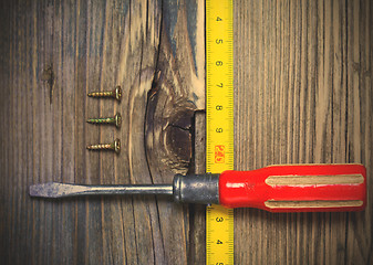 Image showing old screwdriver, three screws and measuring tape 