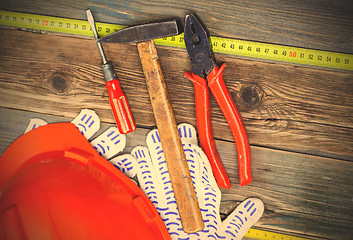 Image showing Vintage pliers, hammer, screwdriver, tape measure, a bright helm