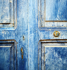 Image showing dirty stripped paint in the blue wood door and rusty nail