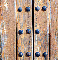 Image showing nail dirty stripped paint in the brown wood door and rusty yello