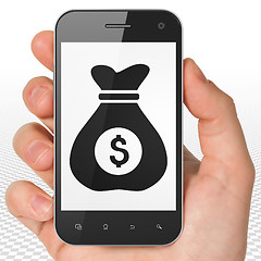 Image showing Finance concept: Money Bag on Hand Holding Smartphone display