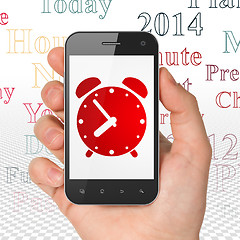 Image showing Timeline concept: Hand Holding Smartphone with Alarm Clock on display