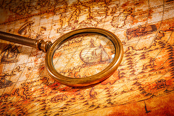 Image showing Vintage magnifying glass lies on an ancient world map