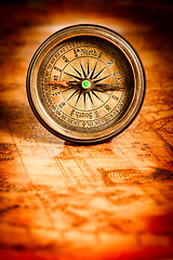 Image showing Vintage compass lies on an ancient world map.