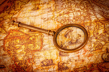 Image showing Vintage magnifying glass lies on an ancient world map