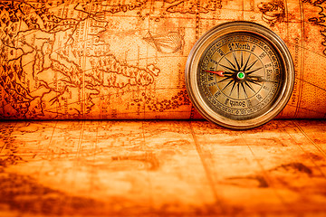 Image showing Vintage compass lies on an ancient world map.