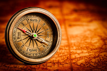 Image showing Vintage compass lies on an ancient world map.