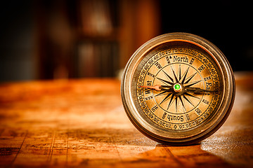 Image showing Vintage compass lies on an ancient world map.