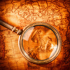 Image showing Vintage magnifying glass lies on an ancient world map