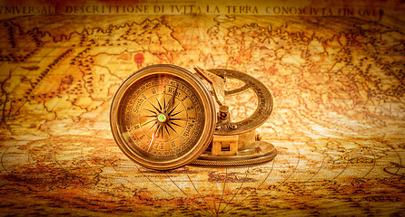 Image showing Vintage compass lies on an ancient world map.