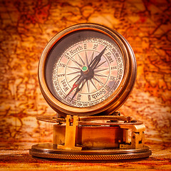 Image showing Vintage compass lies on an ancient world map.