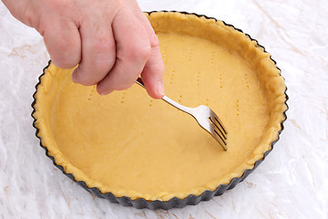 Image showing Woman using fork to prick holes in an uncooked pie crust
