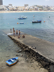 Image showing editorial men are seen on pier Las Canteras Beach with hotels in