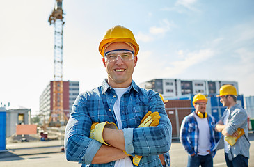 Image showing group of smiling builders in hardhats outdoors