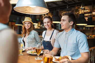 Image showing happy friends eating and drinking at bar or pub