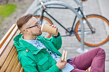 Image showing happy young hipster man with coffee and sandwich