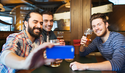 Image showing male friends with smartphone drinking beer at bar