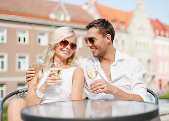 Image showing smiling couple in sunglasses drinking wine in cafe