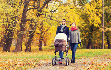 Image showing smiling couple with baby pram in autumn park