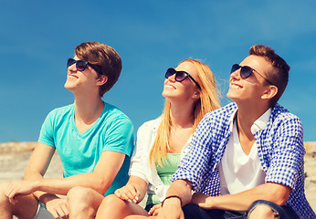 Image showing group of smiling friends sitting on city street