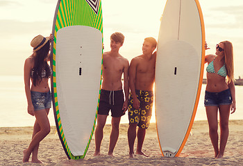 Image showing smiling friends in sunglasses with surfs on beach