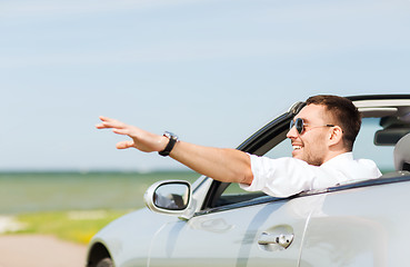 Image showing happy man driving cabriolet car and waving hand