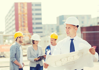 Image showing group of builders with tablet pc and blueprint