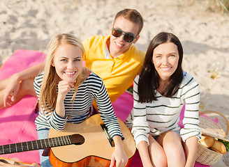 Image showing group of happy friends playing guitar on beach